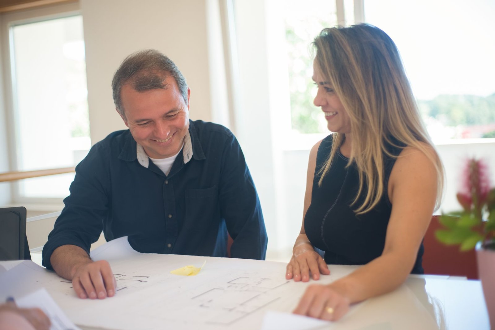 Qué preguntar antes de contratar a un arquitecto – Imagen 1 Reunión inicial entre cliente y arquitecto con planos sobre mesa de trabajo