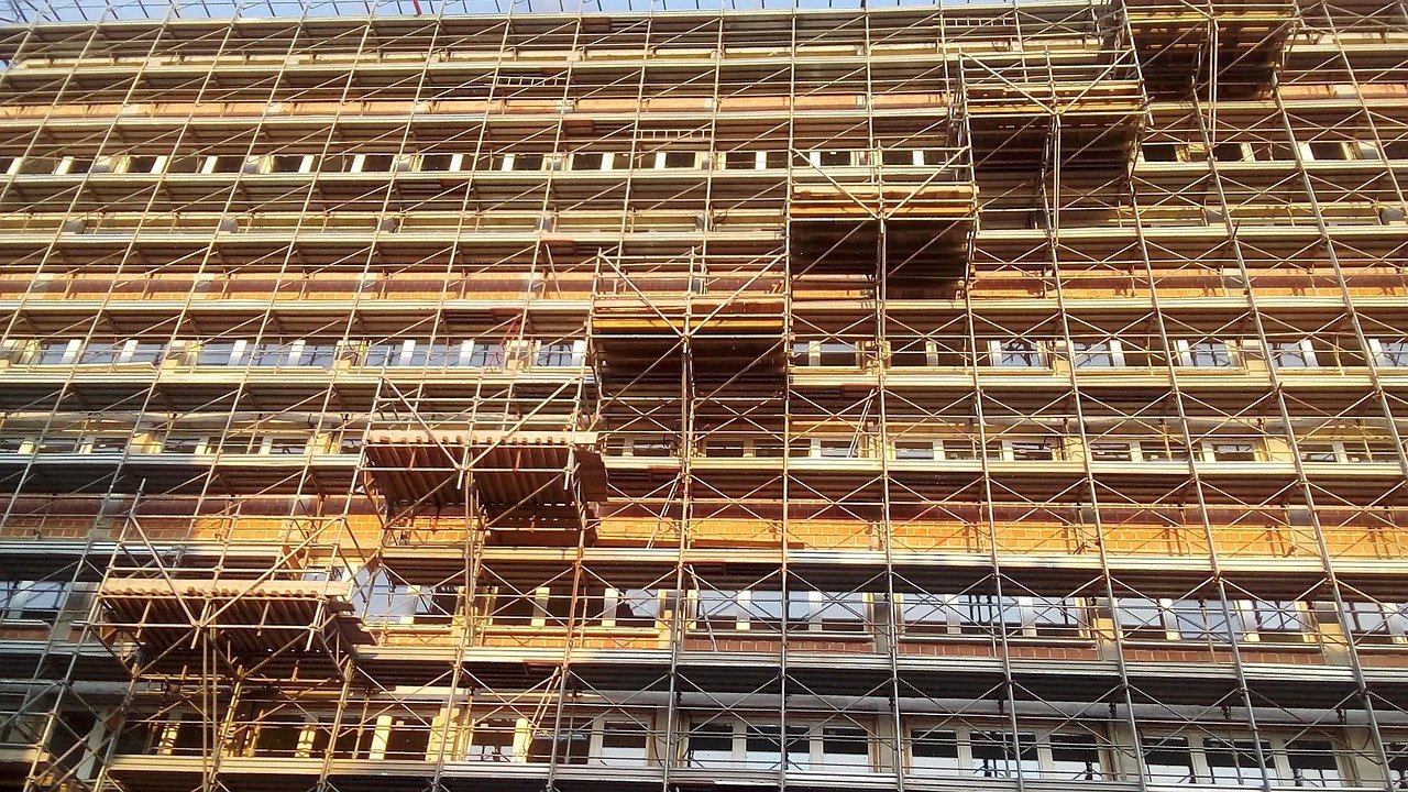 Andamio tubular con lona protectora ocupando la acera durante obras en fachada urbana