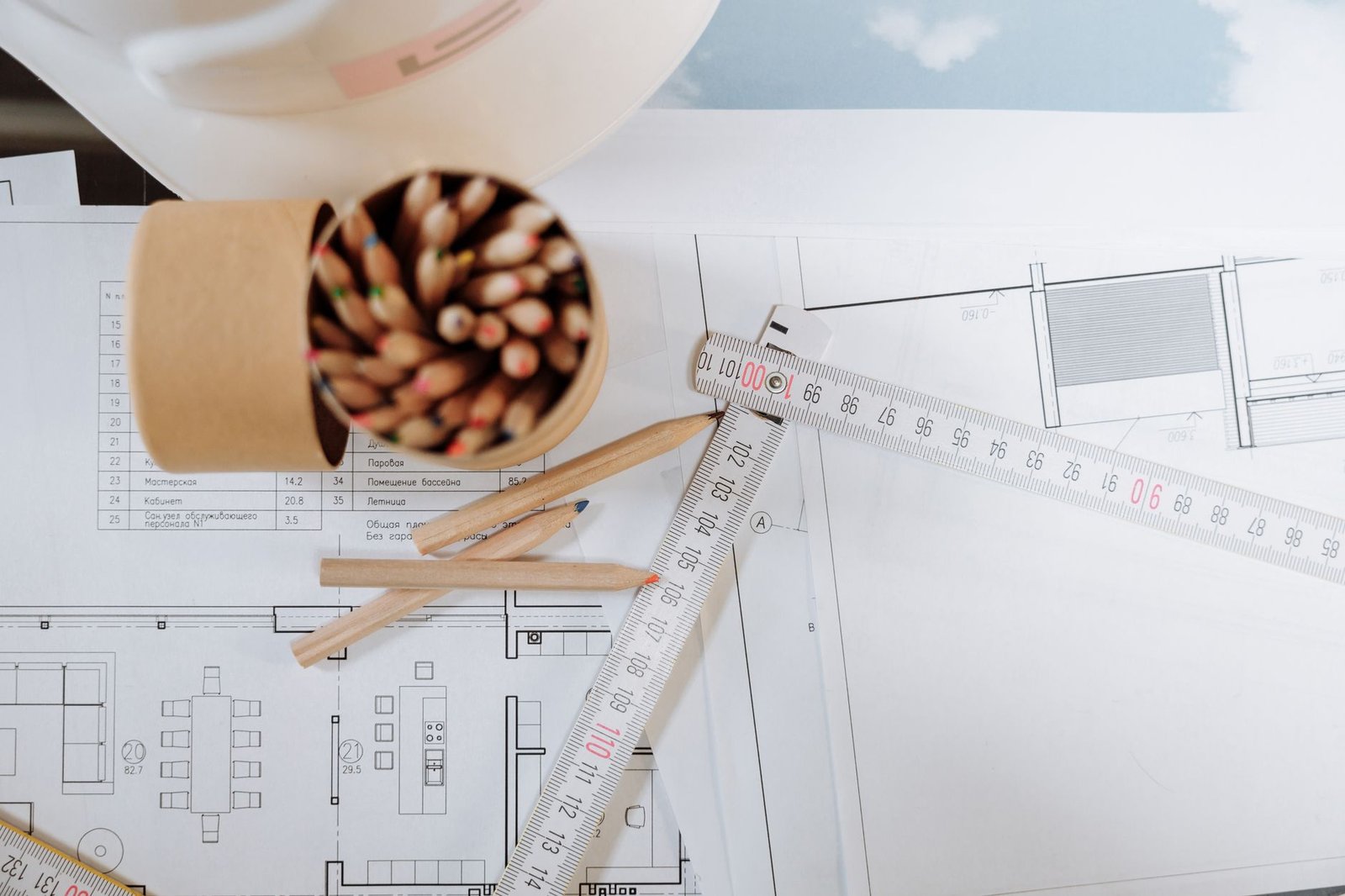 Planos de planta de vivienda sobre mesa de trabajo con escalímetro y lápiz