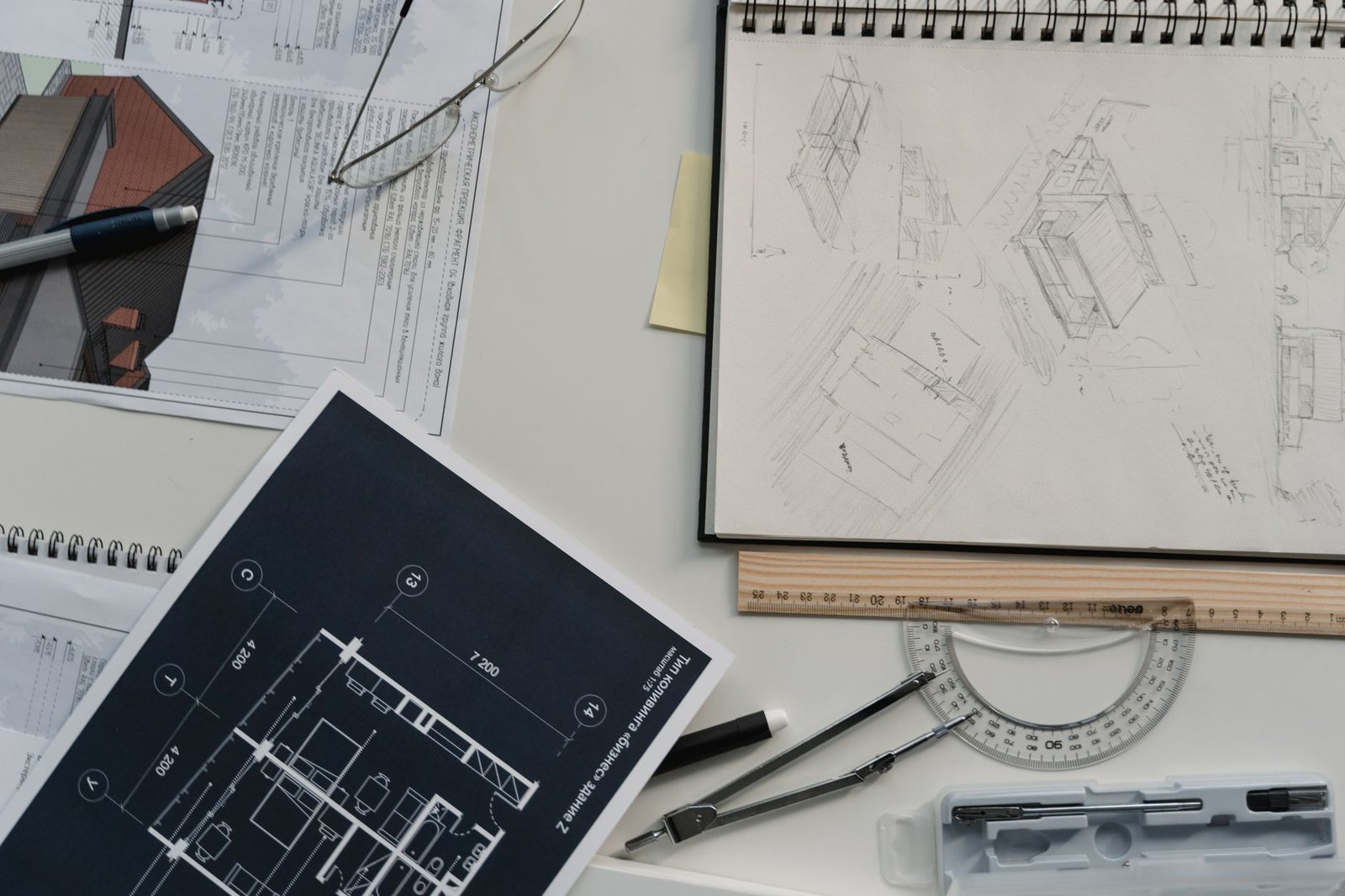 Planos técnicos de vivienda sobre mesa de trabajo con escalímetro y documentación